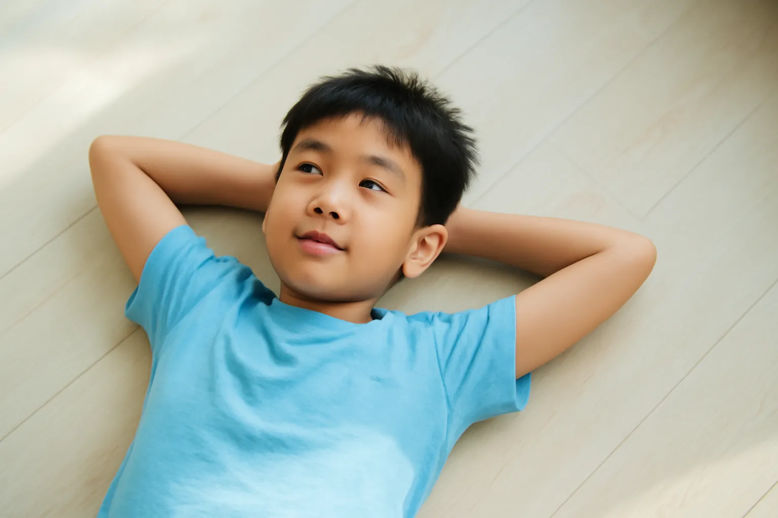 Cậu bé lớp bảy nằm dài trên sàn gỗ nhìn trần nhà thư thái
